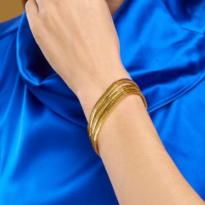 une femme portant une chemise bleue et des bracelets dorés