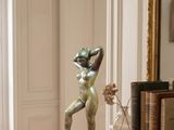 a statue of a woman standing on a table next to a mirror