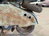 a rusted motorcycle that is parked in a parking lot