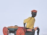 figurine of a man sitting on a cart with a pizza on it