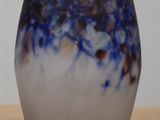 a glass vase sitting on a table with a white wall in the background