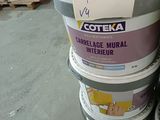 Plusieurs seaux de peinture sont empilés les uns sur les autres dans un entrepôt