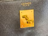 the handle of a black purse with a gold plate on it