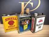 three vintage shell oil cans sitting on top of a wooden table