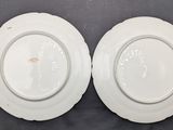 two white plates sitting on top of a table next to each other