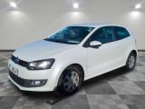 the white volkswagen polo is parked in a room with checkered floor