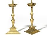 pair of antique brass candlesticks on pedestals on a white background