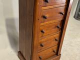 a tall wooden chest of drawers with many drawers