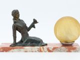 statue of a woman sitting on a marble base with a yellow ball