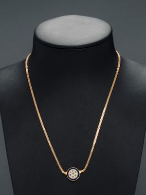 un collier en or orné d'un médaillon noir et blanc sur un mannequin