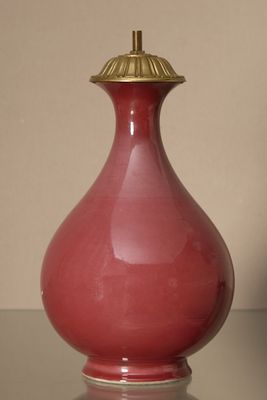 a red vase sitting on a table with a gold lid