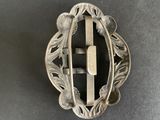 a close up of a silver brooch with a cross on it