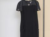 the black dress is hanging on a hanger in front of a yellow wall