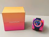 une montre Swatch dans une boîte rose, à côté d'une boîte rose et jaune