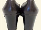pair of brown leather shoes with black heeling on a white background