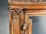 an antique carved wood fireplace mantle with a lion head on the mantle