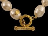 a close up of a necklace with pearls and a gold clasp