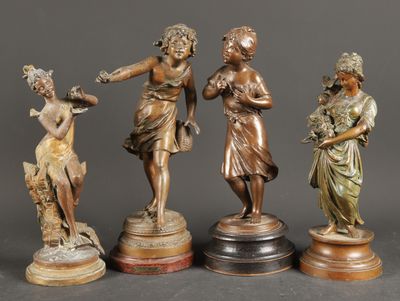 four bronze figurines of women holding flowers and standing on pedestals
