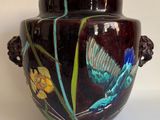 un vase orné d'un papillon peint, posé sur une table