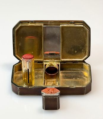 a small metal box with lipstick and other items in it