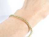 someone is wearing a gold bracelet with a braid design on it