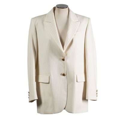 the suit is white and has a gold button on the lapel