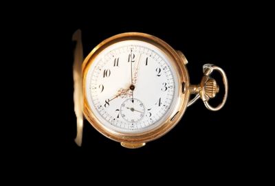gros plan d'une montre de poche en or sur fond noir