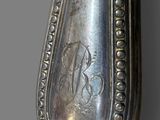 an old silver spoon with a monogram on it sitting on top of a table