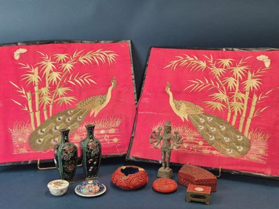 Trois œuvres d'art sont exposées sur une table, aux côtés de vases et d'autres objets