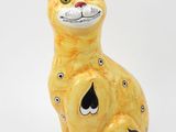 une figurine de chat jaune posée sur une surface blanche