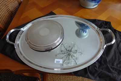 un plateau en argent muni d'un couvercle en verre, posé sur une table