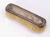 an antique silver plate brush with gold bristles on a white background