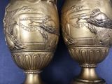 two vases that are sitting side by side on a blue surface