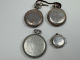 three silver pocket watches and a pair of earrings on a white surface