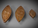 trois plaques en bois sculptées posées sur une surface grise