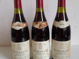 three bottles of red wine are lined up on a table