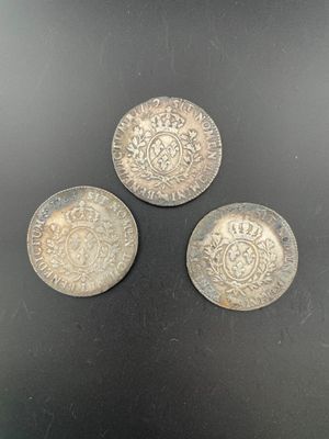 three silver coins sitting on top of a black surface