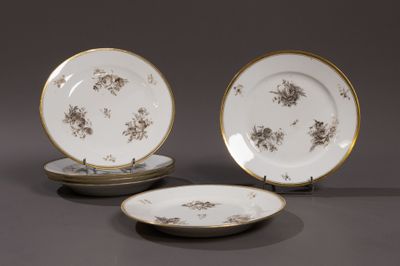 trois assiettes aux bords dorés et ornées de fleurs sur un fond gris