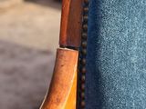 a close up of a wooden chair with a blue upholstered seat