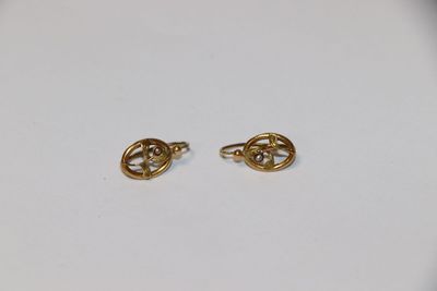 une paire de boucles d'oreilles en or sur une surface blanche