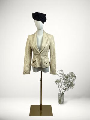 jacket on a mannequin stand with a vase of flowers in the background