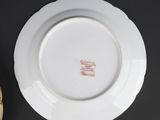 a white plate with a gold rim sitting on a black table
