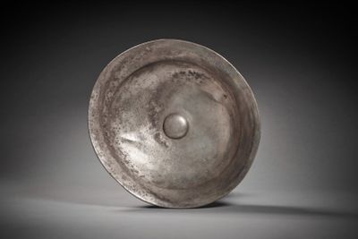 an old metal bowl sitting on top of a white surface