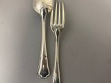 two silver spoons and a fork on top of a table