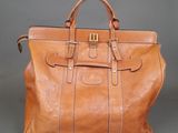 the large brown leather bag is sitting on a gray surface
