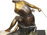 bronze statue of a woman sitting on a rock with a dog on a leash