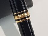 a black pen with a gold band sitting on top of a box