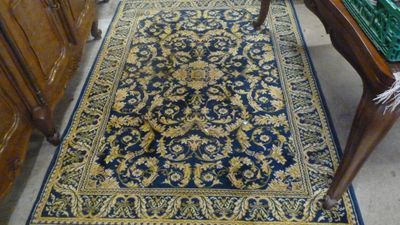 un tapis bleu et or posé sur le sol, à côté d'une commode