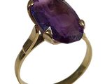 gros plan d'une bague en or avec une pierre violette