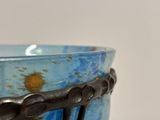 a blue bowl with a black handle on a table
